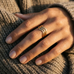 Close-up of the Bali Waves adjustable ring with three wavy gold bands worn on the middle finger