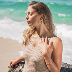 Woman wearing Claire star earrings and Siena chain necklace in gold-plated stainless steel at the beach