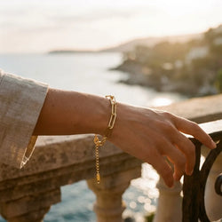 Woman wearing the Riviera Bold chain bracelet in gold-plated stainless steel by the sea